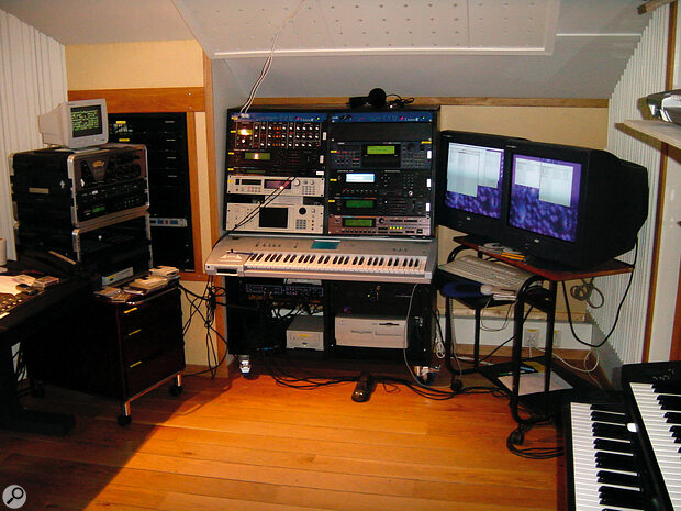 The keyboard area in the room is mainly devoted to sound sources and audio interfaces. The left rack contains a Manley Voxbox voice channel, along with a headphone amp and an Akai MPC3000 sampling workstation. Built into the wall is a rack containing four Digidesign 888 audio interfaces and two Digidesign 882 audio interfaces, plus the studio's master Aardvark Aardsync II word clock generator, an Adams‑Smith Z3 sync unit for the Otari MX80 two‑inch machine, and some balancing units for the keyboards to get their outputs into the console at a higher level. The two keyboard racks both contain Emagic Unitor8 MIDI interfaces, plus (left rack) Studio Electronics SE1, Roland JD990 and JV880 sound modules, Akai S3000XL and S5000 samplers, and (right rack) Yamaha EX5R, Kurzweil K2500R, Roland JV2080 and JV5080 sound modules. The master keyboard is a Korg Triton. Behind the computer screens is the vocal booth.