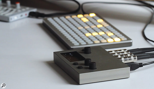 Monome Norns (front) connected to the illuminated button-festooned Monome Grid controller.