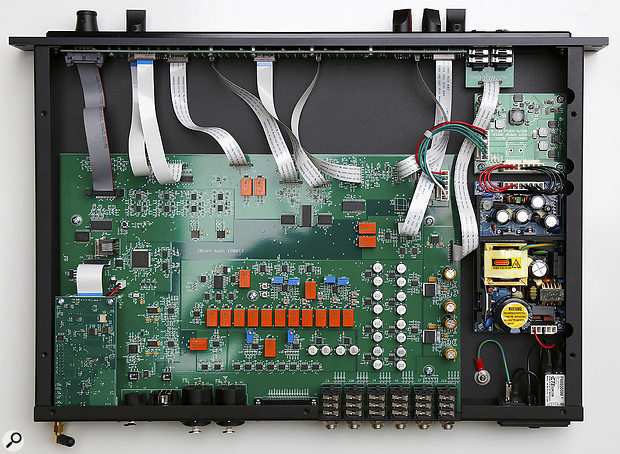 The obligatory internal shot! The switch-mode power supply module on the right generates a  12V DC supply which feeds a  DC-DC converter board delivering ±18V for the analogue circuitry and +5V for the digital control electronics. The array of orange sealed signal–switching relays are obvious, but the large chip above and to the left is the electronic volume control, while the two chunky chips to the right are the headphone amps. The daughter–board on the extreme left provides the Bluetooth and USB interfaces. The square chip with pins on all four sides on the left-hand side is the PIC microcontroller.