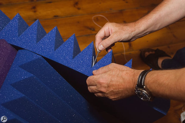 Bella couldn't fix any acoustic treatment permanently, so Paul suggested threading string through pieces of acoustic foam and then hanging them from the picture rail on hooks.