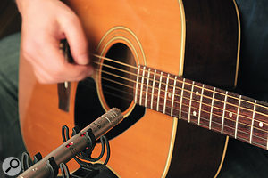 Unless you have time to experiment with mic positioning (which is unlikely for a live show), the safest place to point your mic is the area where the guitar's neck and body meet.