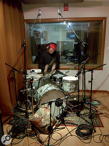 Alt-J drummer Thom Green lays down a rhythm track in the live area at Iguana Studios. This photo shows both his unusual drum kit, with miniature snare drum and no cymbals, and Charlie Andrew's typical miking arrangement. The three Earthworks mics are visible overhead and on the kick drum, where an AKG D112 is also employed. 