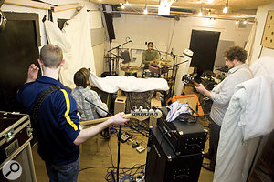 Just because you record a band in one small room doesn’t mean you have to get masses of uncontrollable spill. For example, the full–band session pictured here had both guitar amps within two feet of the kick drum, but the level of spill between them and the drums was amazingly low, simply because the instruments were well–balanced in the room, the amps were directed away from the drums, and the most problematic side–wall reflections were damped with thick quilts.