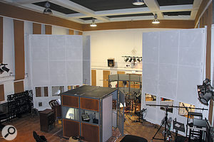 This view of the Studio Two live room illustrates the general setup that stayed in place throughout the session. In the foreground is the temporary vocal booth, while the large white screens have been pulled away from the walls to create isolation areas for the guitar amps and control the acoustic environment around the drums. Two of the ambient mics — a pair of Neumann U67s — are just visible either side of the vocal area.