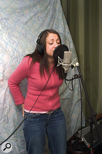 Here you can see the kind of setup that usually yields good results in the home studio. A cardioid microphone is mounted in a suspension shockmount and protected from breath blasts using a pop shield. The vocalist sings within 12 inches of the microphone and with her back to a suspended duvet to avoid sound reflecting off the wall behind her into the sensitive side of the mic.